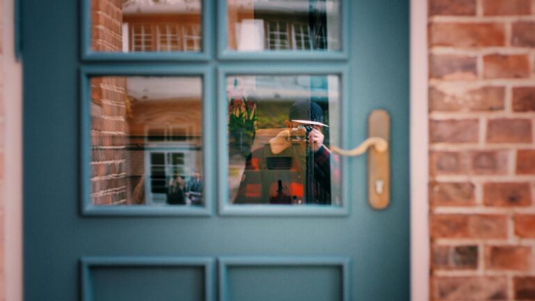 A photographer's reflection captured in a window with a brick wall background.