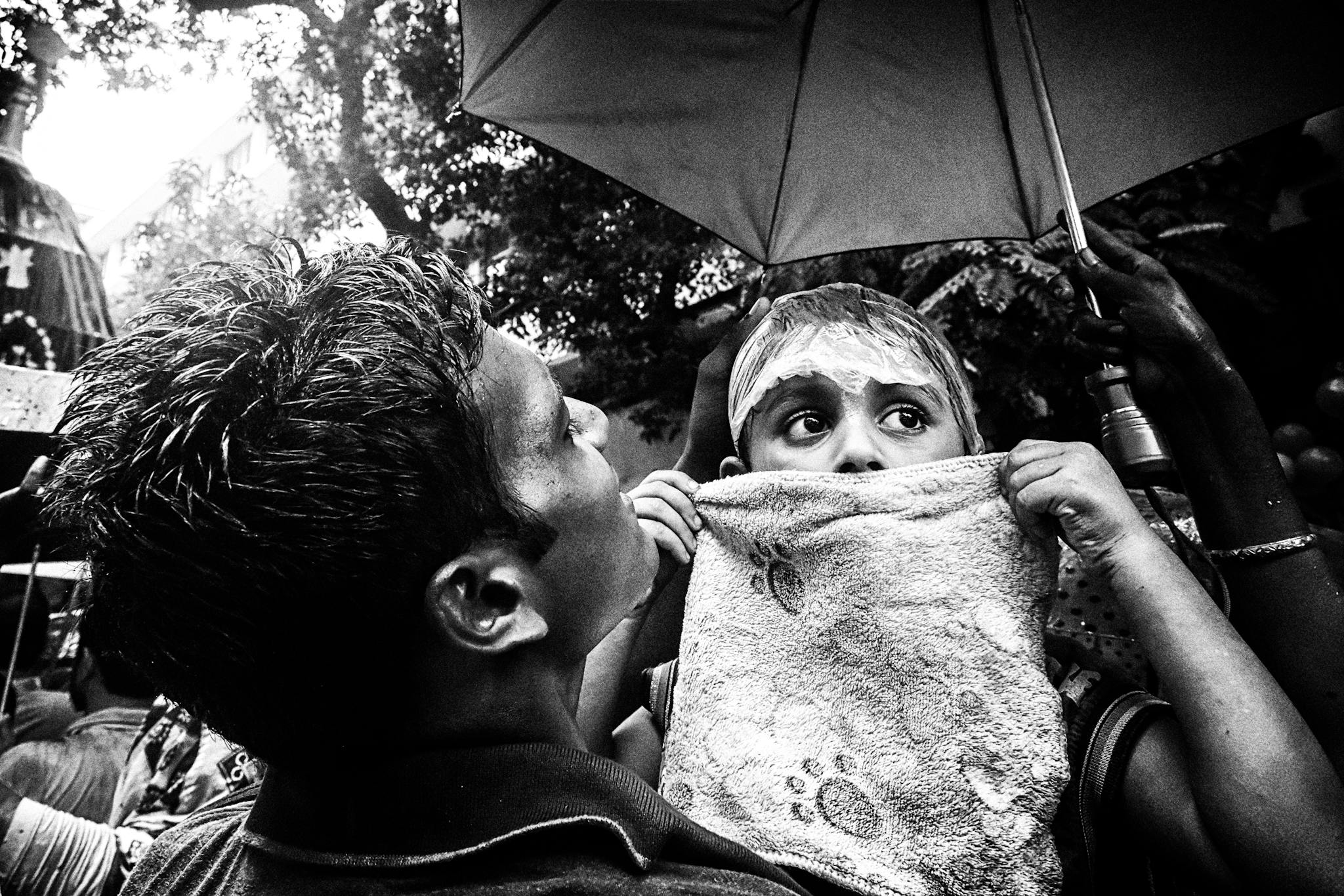 Captivating black and white street photo capturing two people under an umbrella with expressive faces.